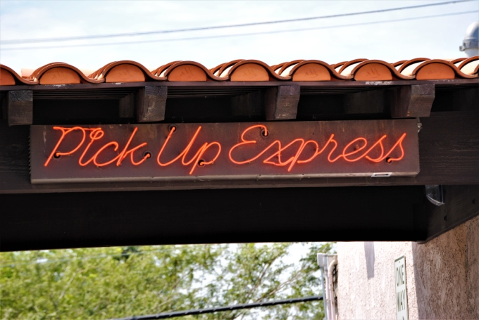 Red neon script sign on a tiled roofline